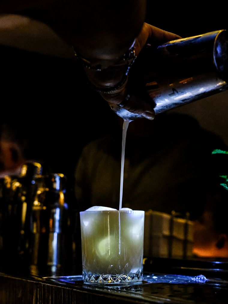 Bartender colando un cóctel sobre la barra
