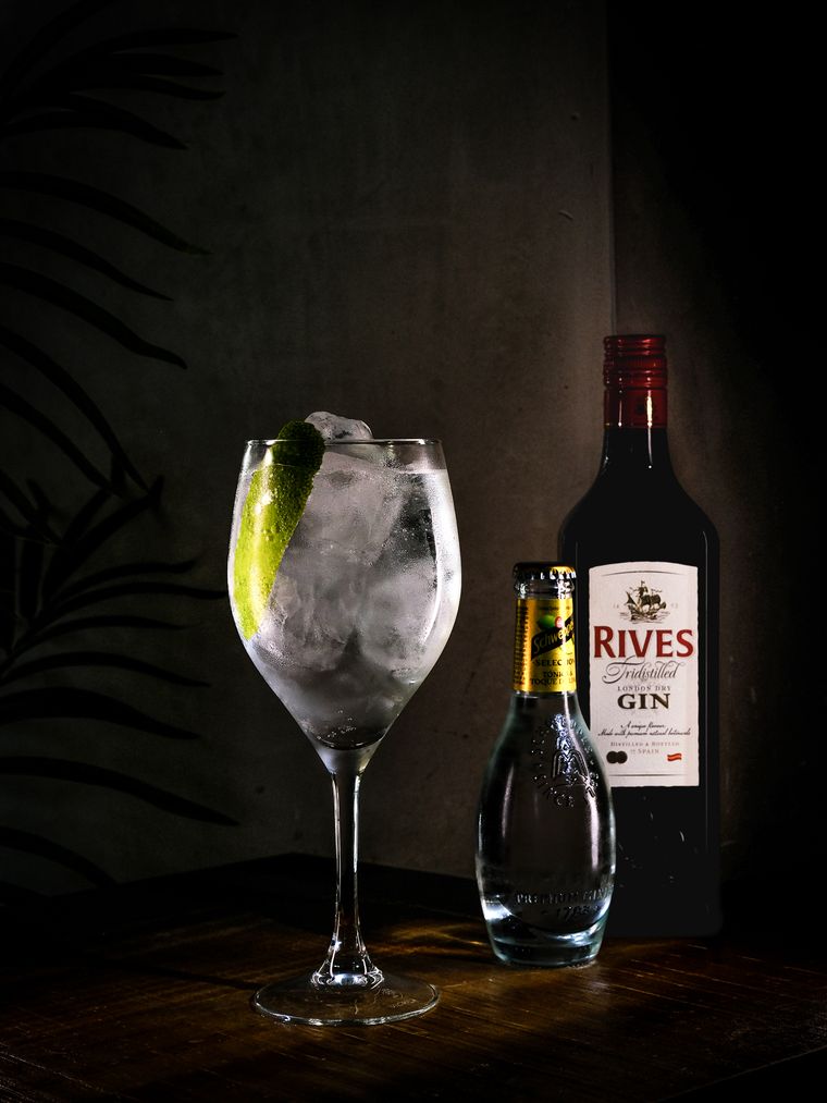 Gin tonic en copa de balón junto a la botella de ginebra