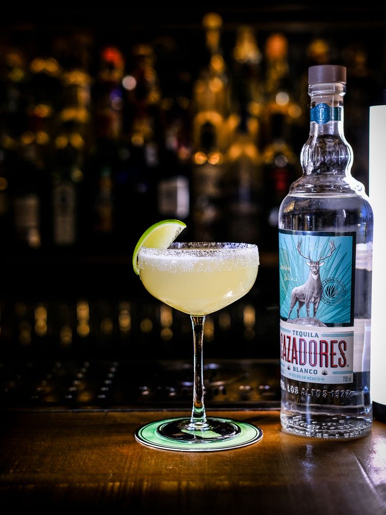 Margarita con lima y sal junto a la botella de tequila